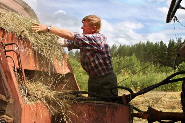 Harvesting hay baler, russian farmer tractor-driver repair used agricultural machinery. clipart