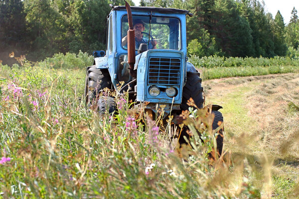 Farming tractor working in field of freshly cut during hayfield.