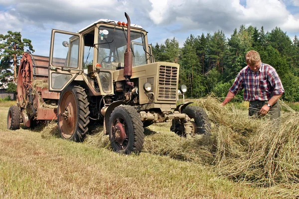 Pola rolników, agronom ciągnika kierowca w pracy kontroli świeżego siana. — Zdjęcie stockowe