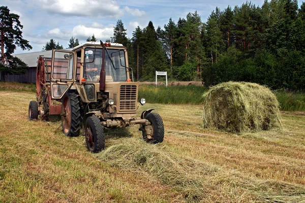 Rundballenpresse kippt einen frisch gerollten Heuballen aus. — Stockfoto