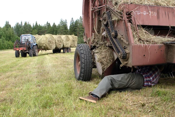 Agricoltore riparazione rotopressa, in campo, durante il fieno . — Foto Stock