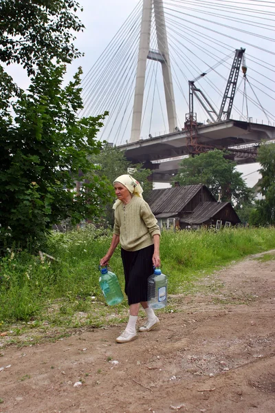Elderling, who lives in house under bridge, goes for water. — Stock Photo, Image