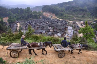 Two carts with Chinese peasants passing along mountain road, spring. clipart