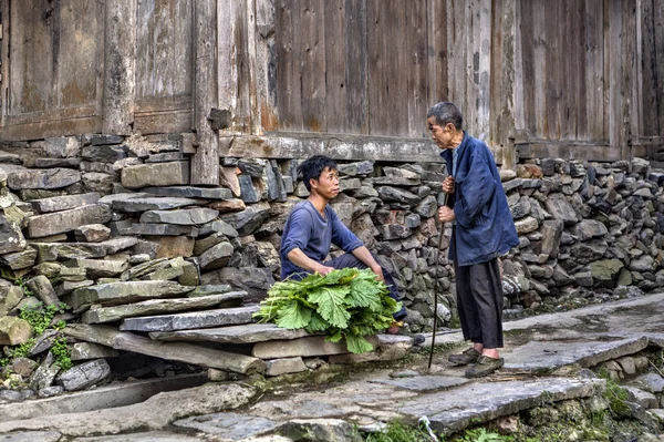 Staré a mladší farmáři mluví poblíž dřevěné kůlny. — Stock fotografie