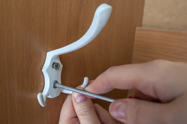 Hand with screwdriver, screw the hook for clothes in wardrobe. — Stock Image Hand with screwdriver, screw the hook for clothes in wardrobe. Stock Photo