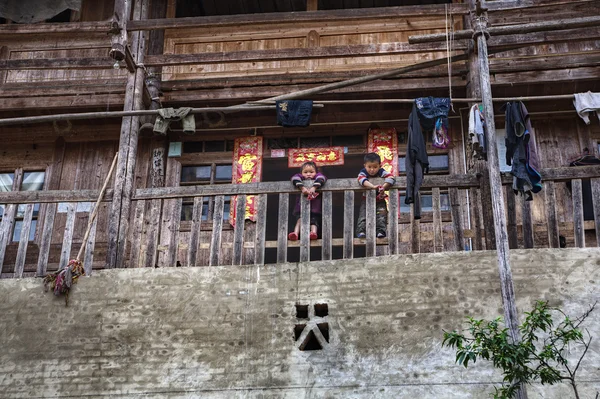 Rural Asian children stand on terrace of Chinese wooden farmhouse. — Stock Photo, Image