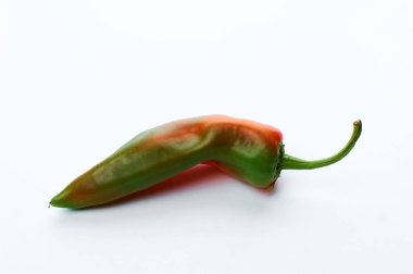 Bir kapsül kırmızı, olgunlaşmamış biber. Beyaz arkaplanda.