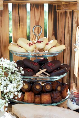 Tatlı masasının bir parçası. Kek başı belaya girer ve siyah çikolata ve cannele. Dekorasyon biçiminde Gypsophilia, tahta arka plan.