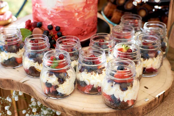 Desserts in a glass jar. Dessert with butter cream and fresh berries, blueberries, currants, strawberries and raspberries.