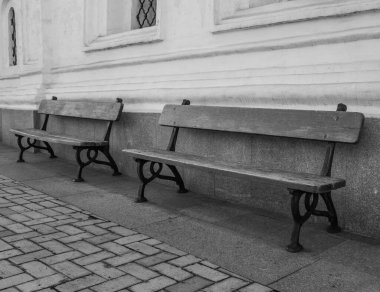 Eski bir binanın duvarının yanında iki bank.