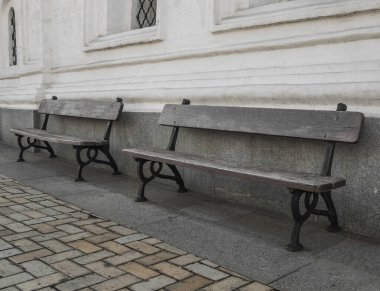 Eski bir binanın duvarının yanında iki bank.