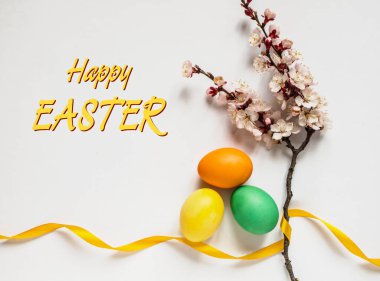 Renkli yumurtalar, sarı kurdele ve çiçekli dallarla Paskalya kompozisyonu