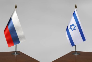 Rusya ve İsrail 'in masa üstü bayrakları gri bir arka planda karşı karşıya