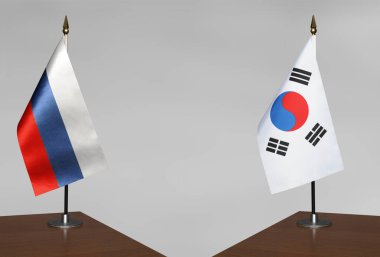 Rusya ve Güney Kore 'nin masa üstü bayrakları gri bir arka planda karşı karşıya