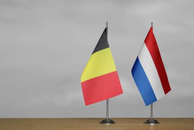 Belçika ve Hollanda 'nın masa üstü bayrakları; gri bulanık arkaplanda duruyor