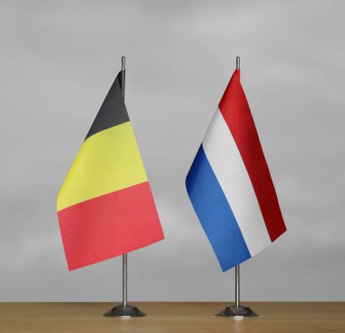 Belçika ve Hollanda 'nın masa üstü bayrakları; gri bulanık arkaplanda duruyor