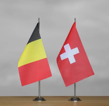 Gri arka planda duran Belçika ve İsviçre 'nin masa üstü bayrakları