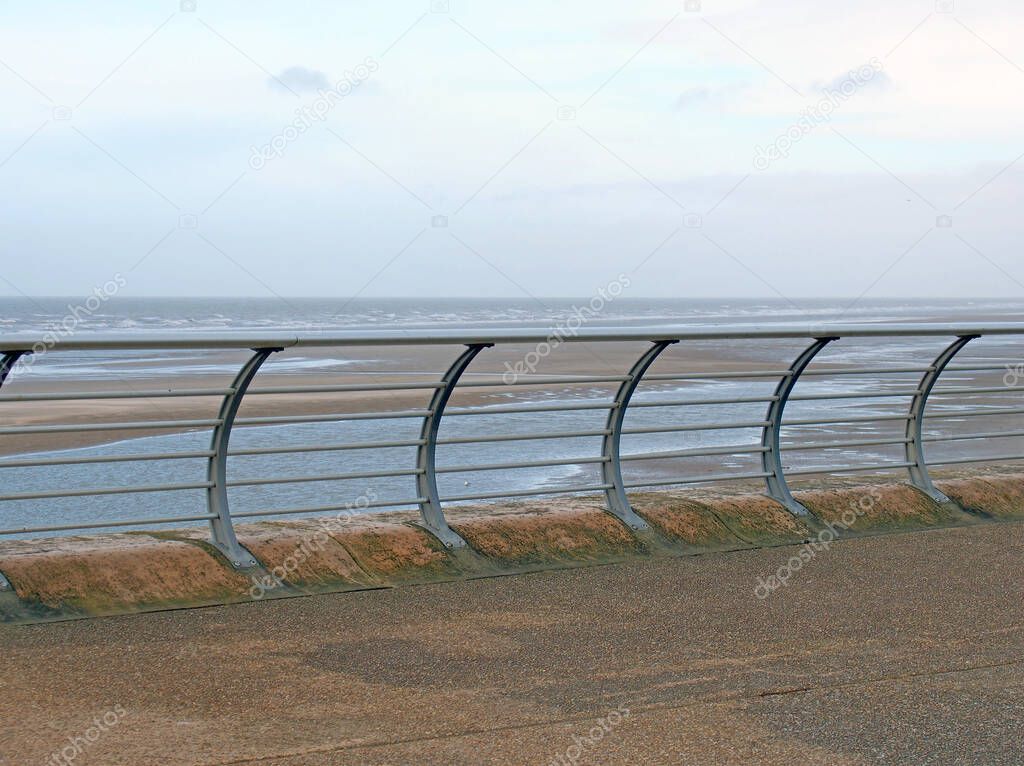 curved metal railings on the seafront in blackpool with waves breaking in the distance