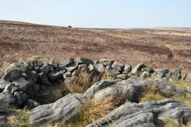 Calderdale, Batı Yorkshire 'daki Midgley bataklığında yer alan değirmencilerin mezarı olarak bilinen Cairn' in tepesindeki taşları ortaya çıkardı.