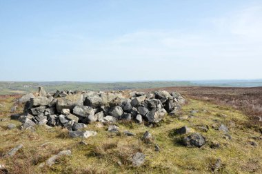 Calderdale, Batı Yorkshire 'daki Midgley bozkırındaki değirmencilerin mezarı olarak bilinen Cairn' in tepesindeki çıplak taşlar Pennine manzarası ve uzaklıktaki Calder Vadisi.
