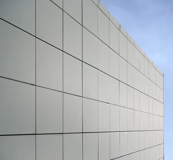 geometric blue metallic cladding modern facade in perspective view with blue sky