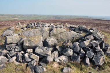 Calderdale, Batı Yorkshire 'daki Midgley bozkırındaki değirmencilerin mezarı olarak bilinen Cairn' in tepesindeki çıplak taşlar Pennine manzarası ve uzaklıktaki Calder Vadisi.