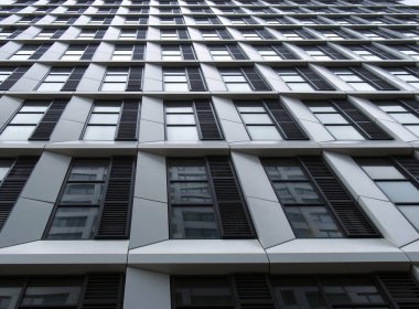 Geometrik beyaz kaplamalı ve koyu pencereli yüksek katlı modern apartmanın perspektif detaylarını kapat