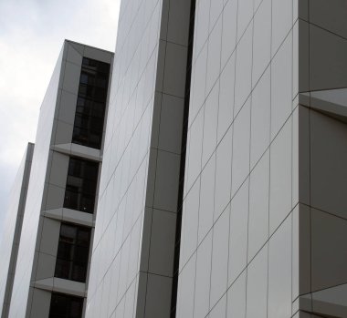 Yüksek katlı, beyaz kaplamalı ve koyu pencereli modern apartmanların detaylarını kapat.