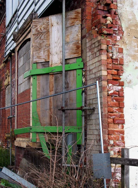 レンガの壁を崩壊させ窓を塞いだ廃墟の古い家のファサード — ストック写真