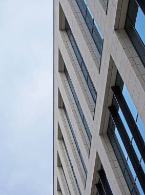 Mavi bulutlu gökyüzü olan modern bir ofis binasına yakın açıda.