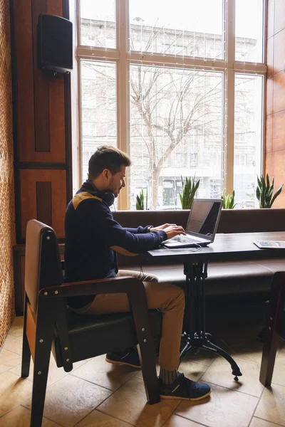 Man met koptelefoon op zijn nek die op laptop werkt — Stockfoto