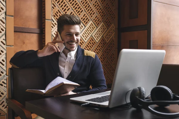 Hombre joven sentado en la mesa y hablando en el teléfono inteligente — Foto de Stock