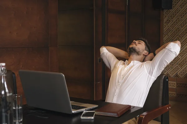 Empresário cansado com os olhos fechados esticando na cadeira — Fotografia de Stock