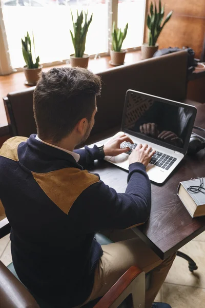 Młody mężczyzna siedzący przy stole podczas pisania na laptopa — Zdjęcie stockowe