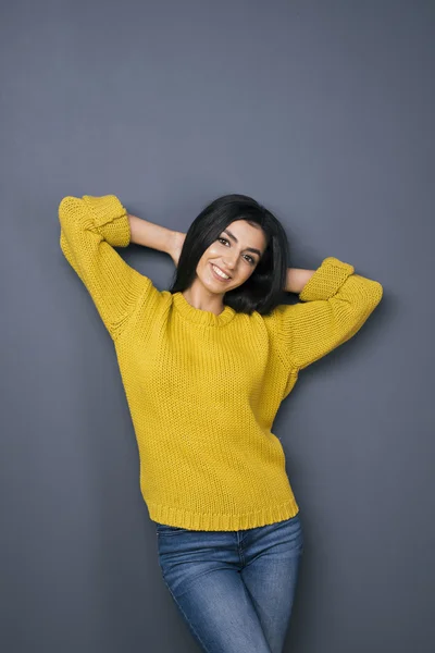 Estudio de chica de pelo negro sonriente con los brazos detrás de la cabeza — Foto de Stock