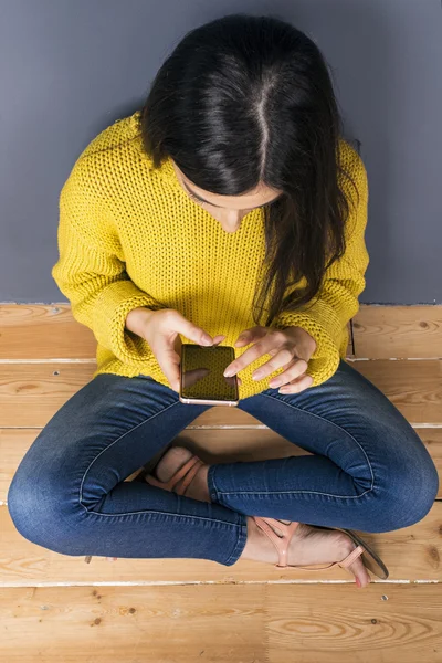 Close-up of model using cell with crossed legs — Stock Photo, Image