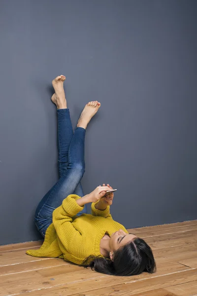 Босоногая девушка использует камеру, лежа вверх ногами на полу. — стоковое фото