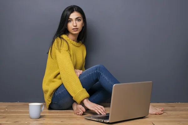 Hermosa chica tranquila con ordenador portátil y taza en el suelo —  Fotos de Stock