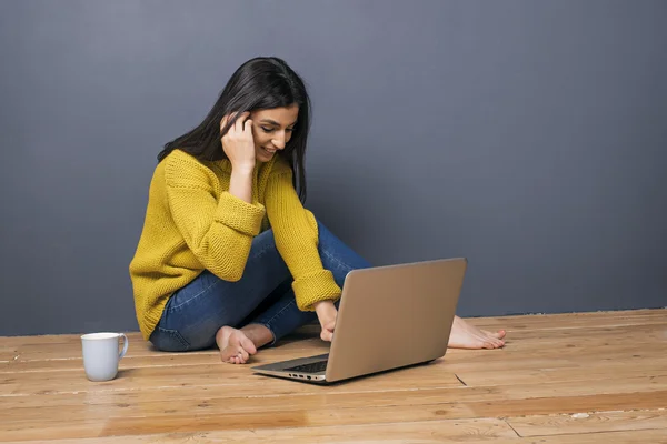 Barefoot smiling girl using laptop on floor — Stock Photo, Image