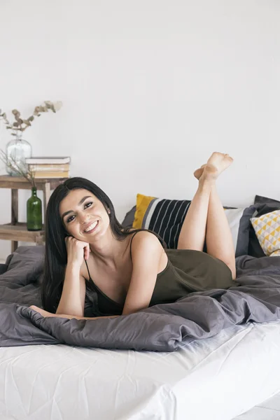 Cheerful Armenian girl smiling at camera in morning bedroom — Stock Photo, Image