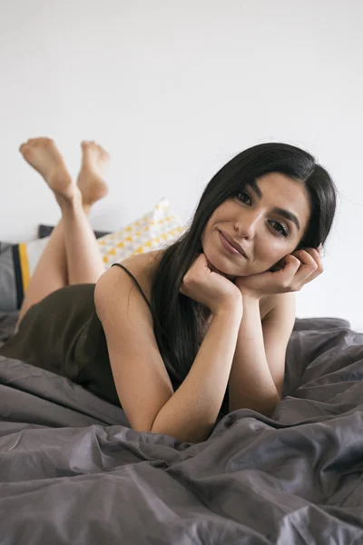 Portrait of smiling young girl on duvet — Stock Photo, Image