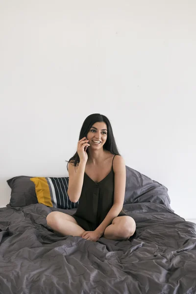 Laughing beautiful girl talking over cell on bed — Stock Photo, Image