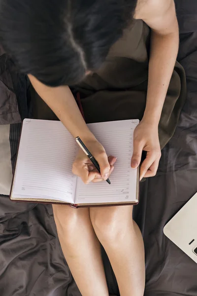 Sopra la testa della ragazza che scrive nel taccuino sul letto — Foto Stock