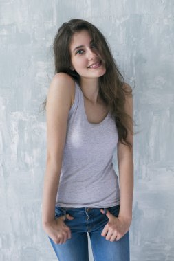 Sevimli genç kız gri çimento duvara karşı kamera poz