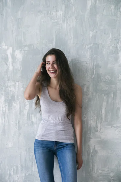 Laughing brunette looking away against of grey wall — Stock Photo, Image