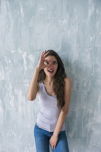 Young brunette looking through ok gesture — Stock Photo, Image