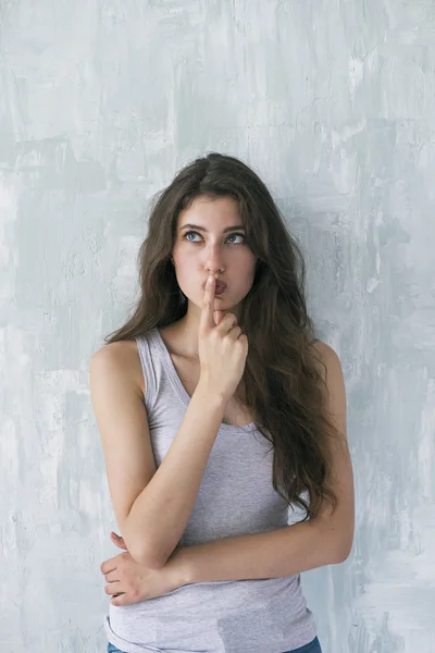 Attractive brunette thinking with finger on lips — Stock Photo, Image