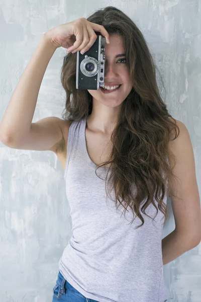 Jonge brunette kijken camera en bijten lip terwijl nemen van foto met camera — Stockfoto