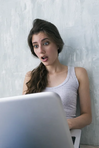 Girl with wide-opened eyes looking at laptop — Stock Photo, Image