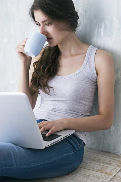 Porträt einer Brünetten mit Tasse mit Laptop — Stockfoto